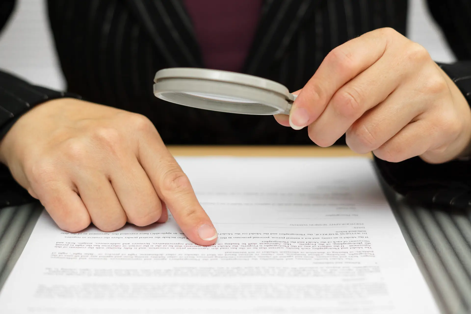 Close-up of a professional reviewing a document with a magnifying glass