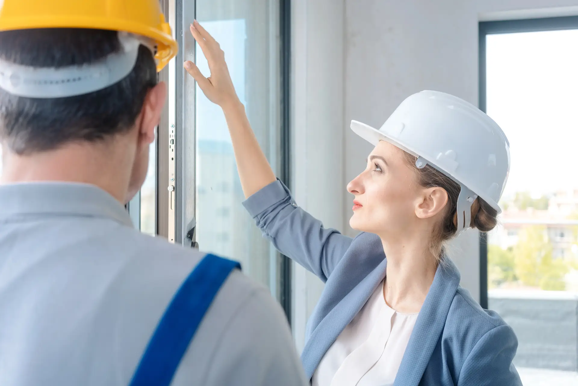 Female inspector in hard hat evaluating window during a field inspection