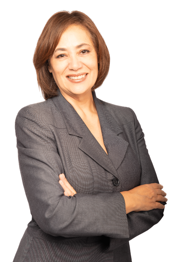 A woman with short brown hair, wearing a grey business suit, smiles confidently with her arms crossed against a plain white background.